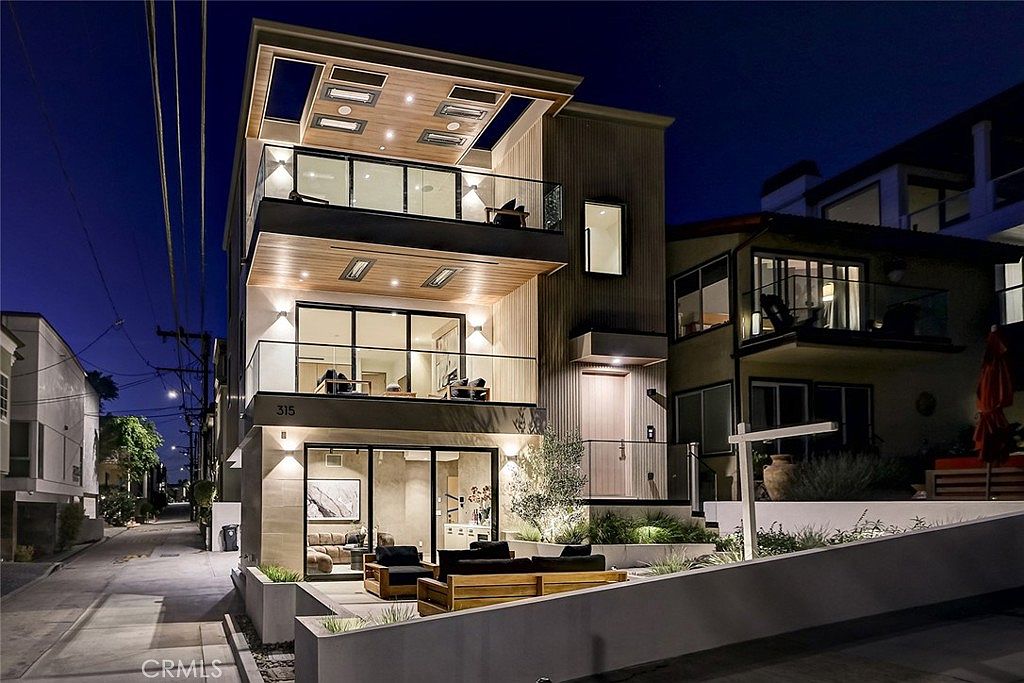 Twilight exterior of 315 25th Street, a custom three-story modern coastal residence in Manhattan Beach with illuminated balconies and corner walk-street position