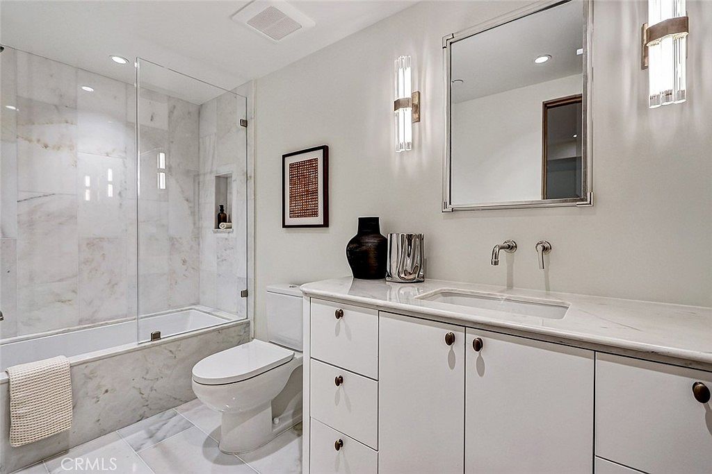 Bathroom finished in Calacatta marble with custom mirror and silver sconces